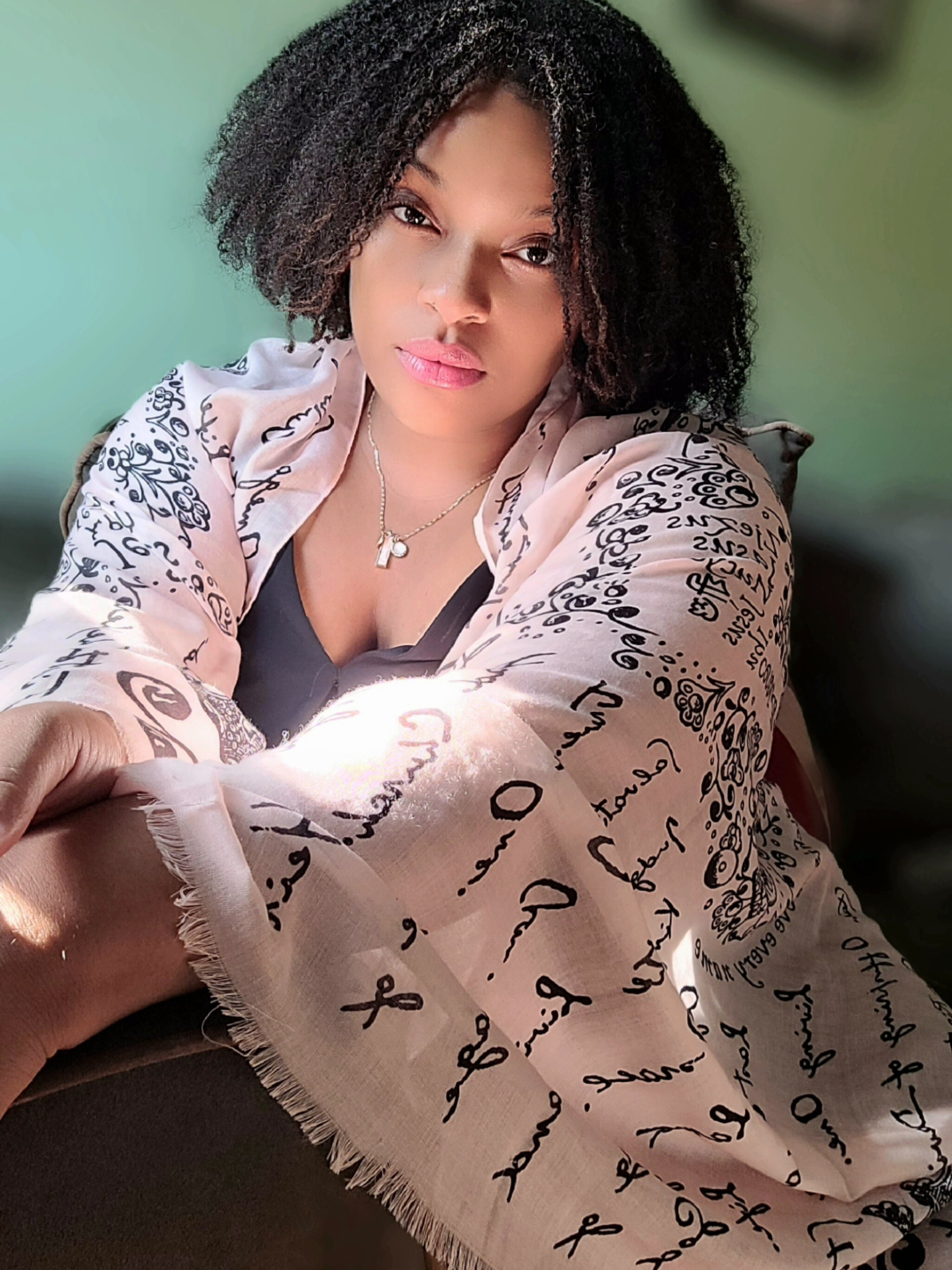 And He Shall Be Called prayer scarf by Prayer Scarves® draped around a woman’s arms, showcasing handwritten script and the names and titles of Jesus throughout the design