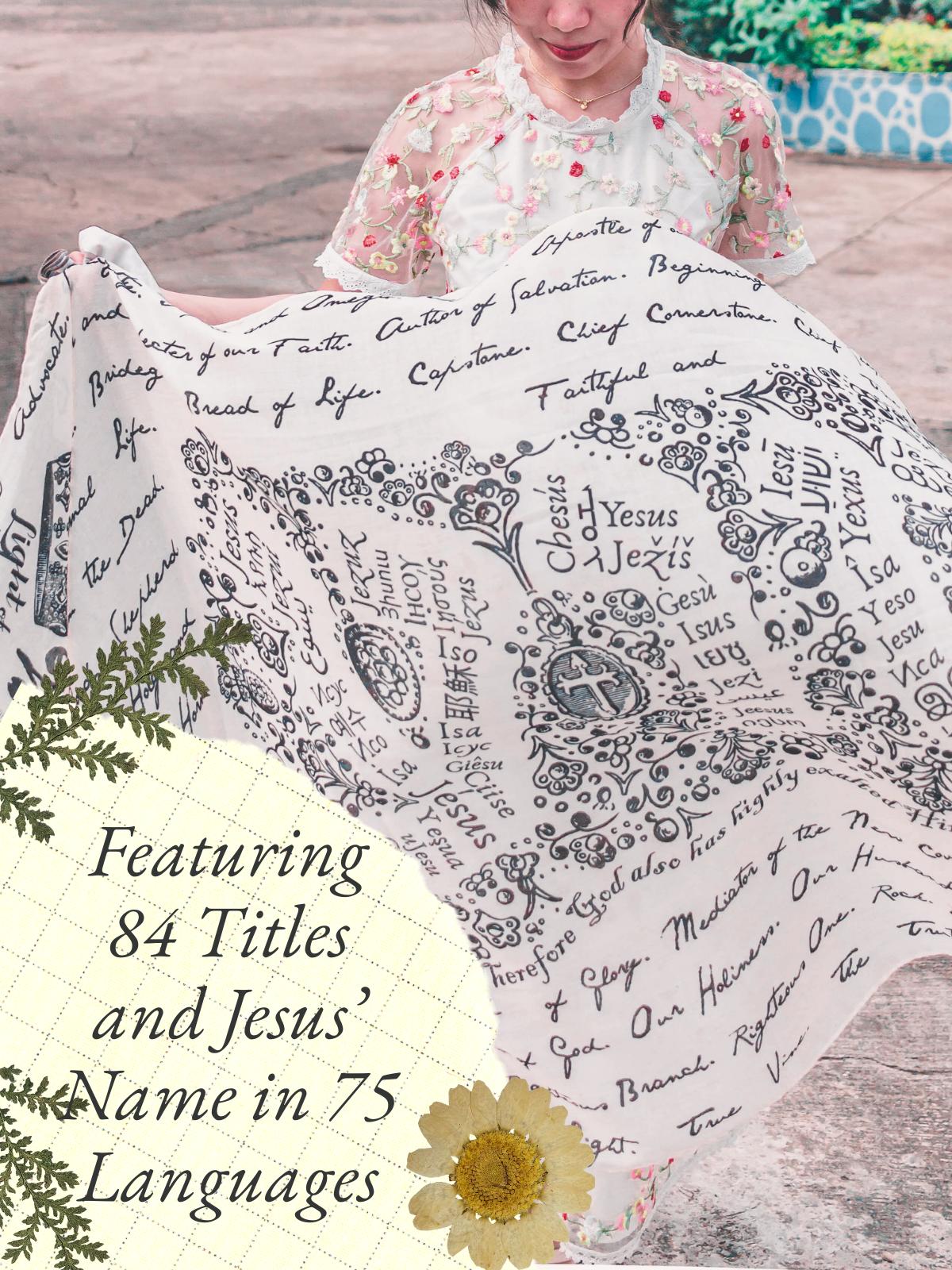 And He Shall Be Called prayer scarf by Prayer Scarves® held open by a woman outdoors, displaying illustrated titles of Jesus and His name written in multiple languages across the fabric
