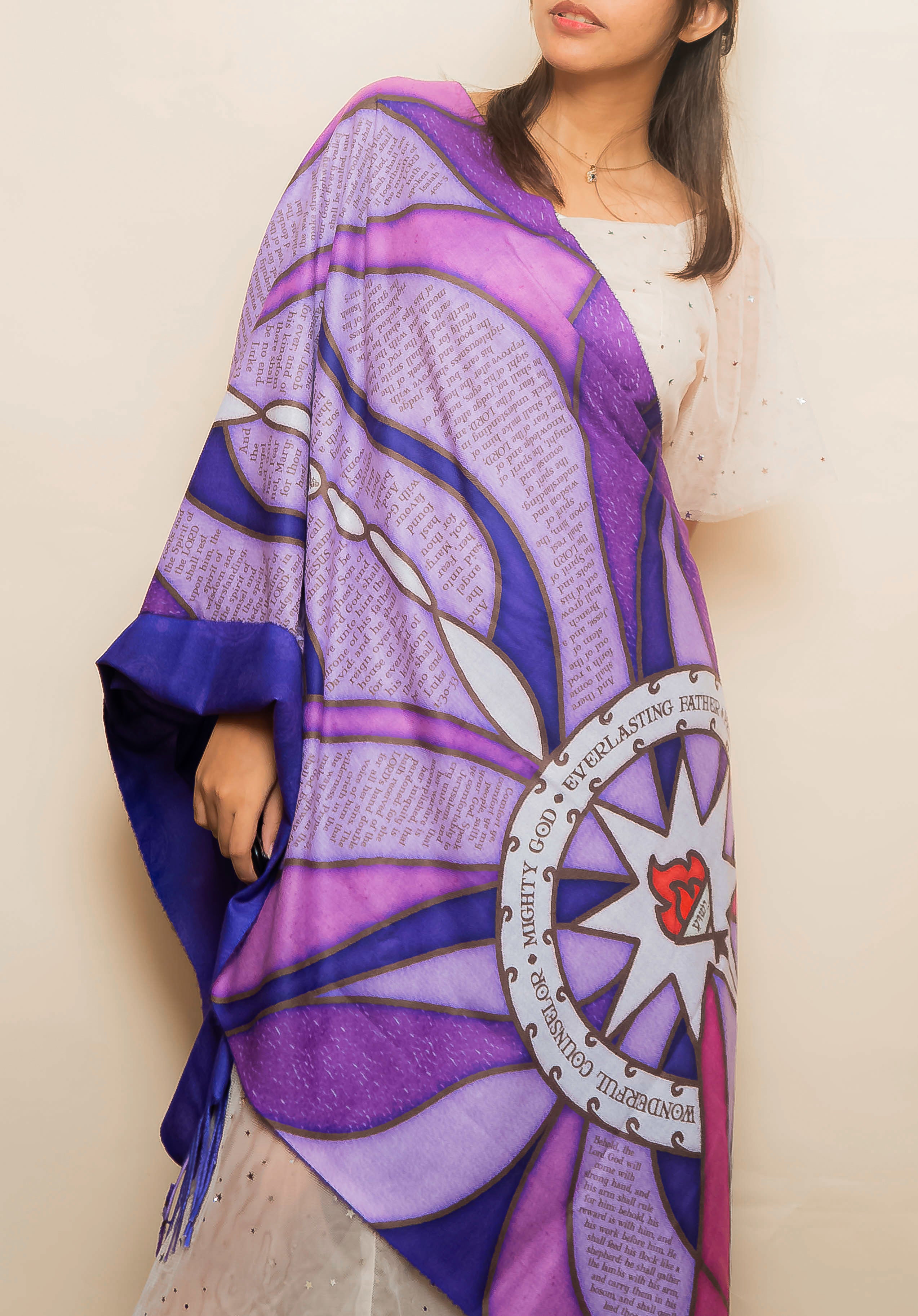 Model wearing the Advent Prayer Scarf™ in rich purple tones, displaying scripture verses and a starburst design inspired by traditional stained glass.