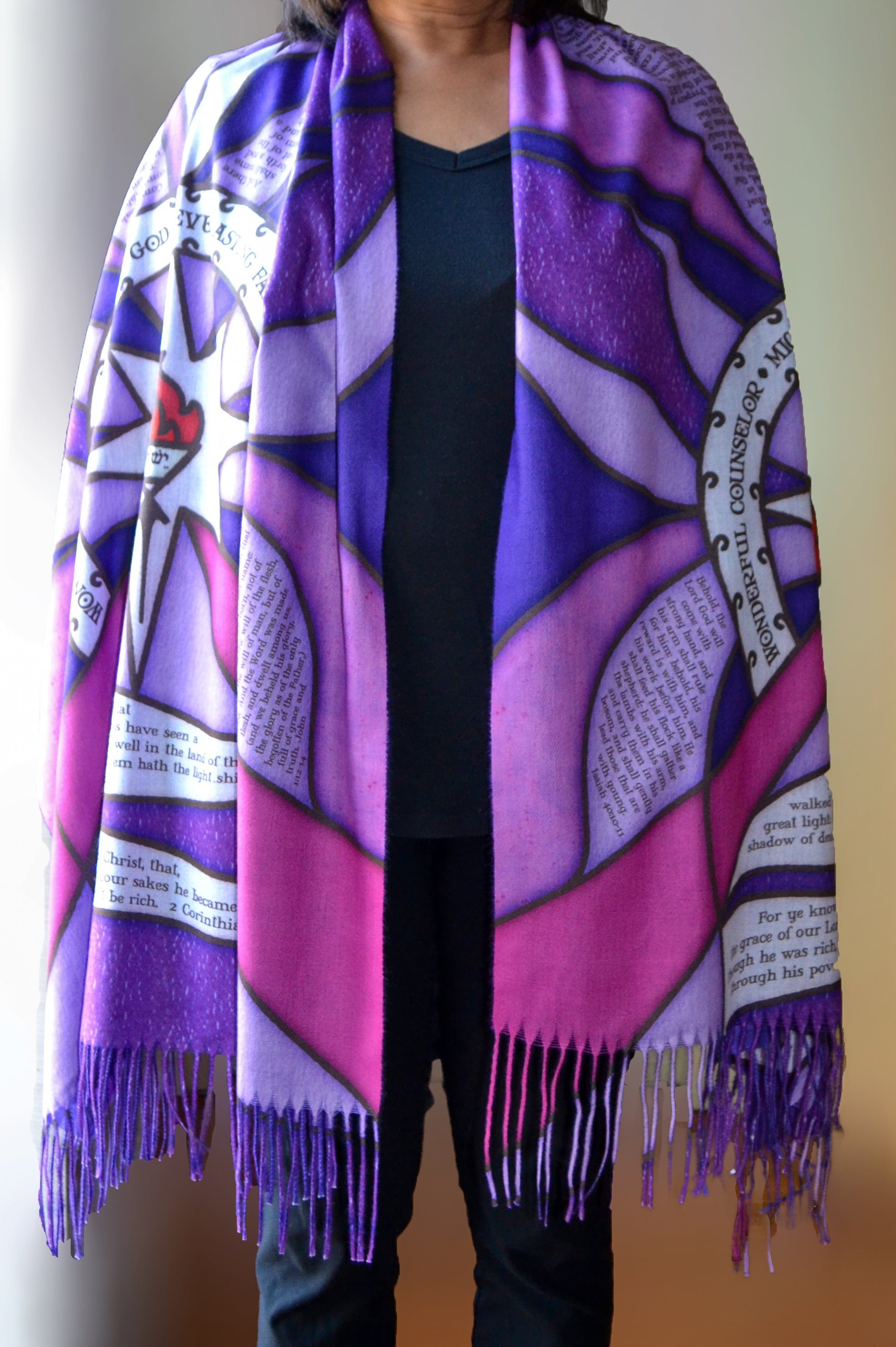 Model wearing the Advent Prayer Scarf™ in rich purple tones, displaying scripture verses and a starburst design inspired by traditional stained glass.