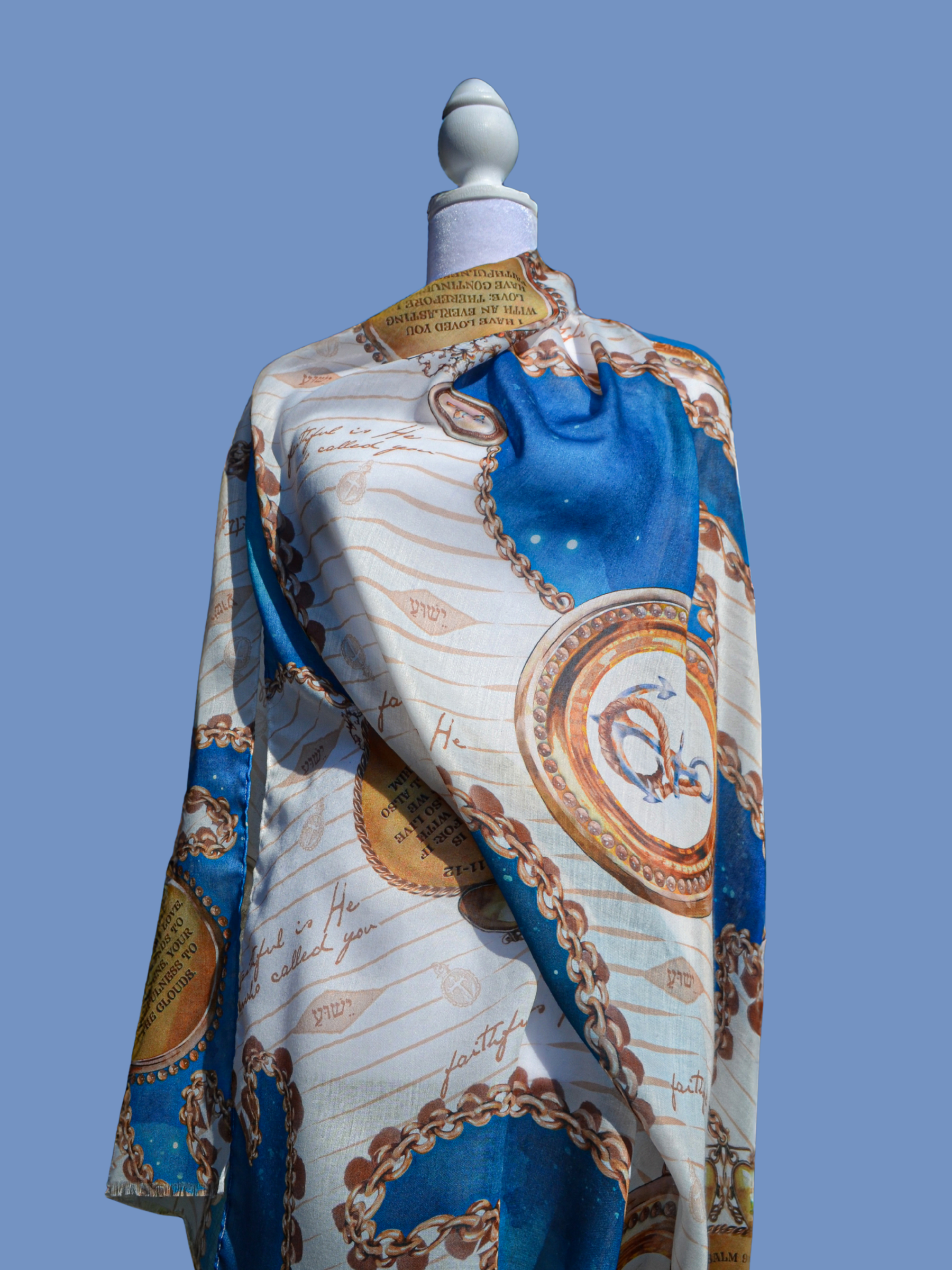 Faithfulness Prayer Scarf by Prayer Scarves® displayed on a mannequin, showing blue and teal sections, gold chain and medallion motifs, handwritten-style script elements, and circular areas of printed scripture text.