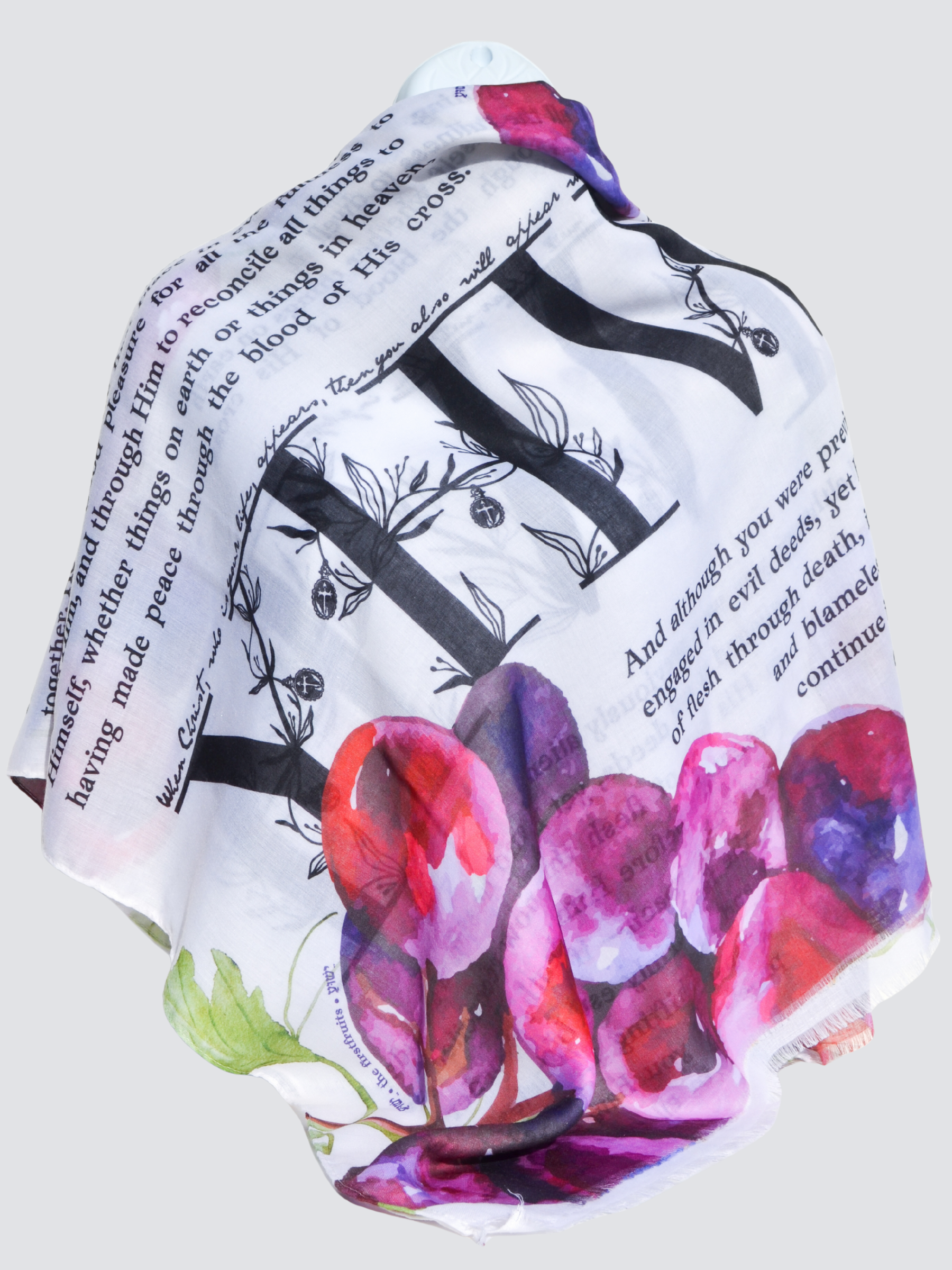 Prayer Scarves® Firstfruits Prayer Scarf draped on a mannequin, featuring bold black scripture text, watercolor grapes in pink and purple, and botanical details on a lightweight white scarf.