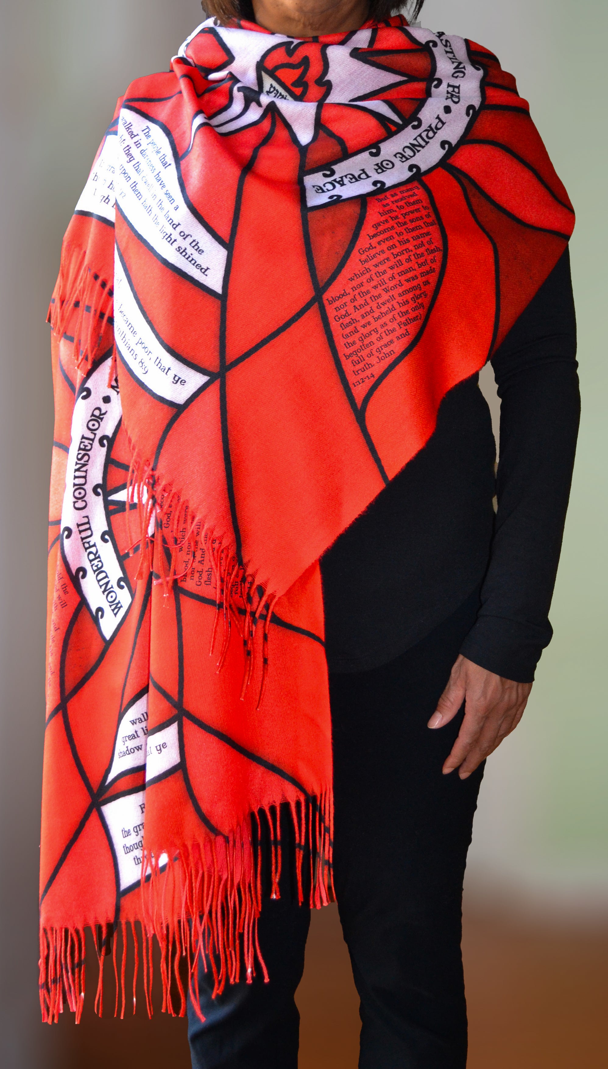 Model wearing the Advent Prayer Scarf™ in red tones, featuring a stained-glass–inspired design with scripture text woven throughout.