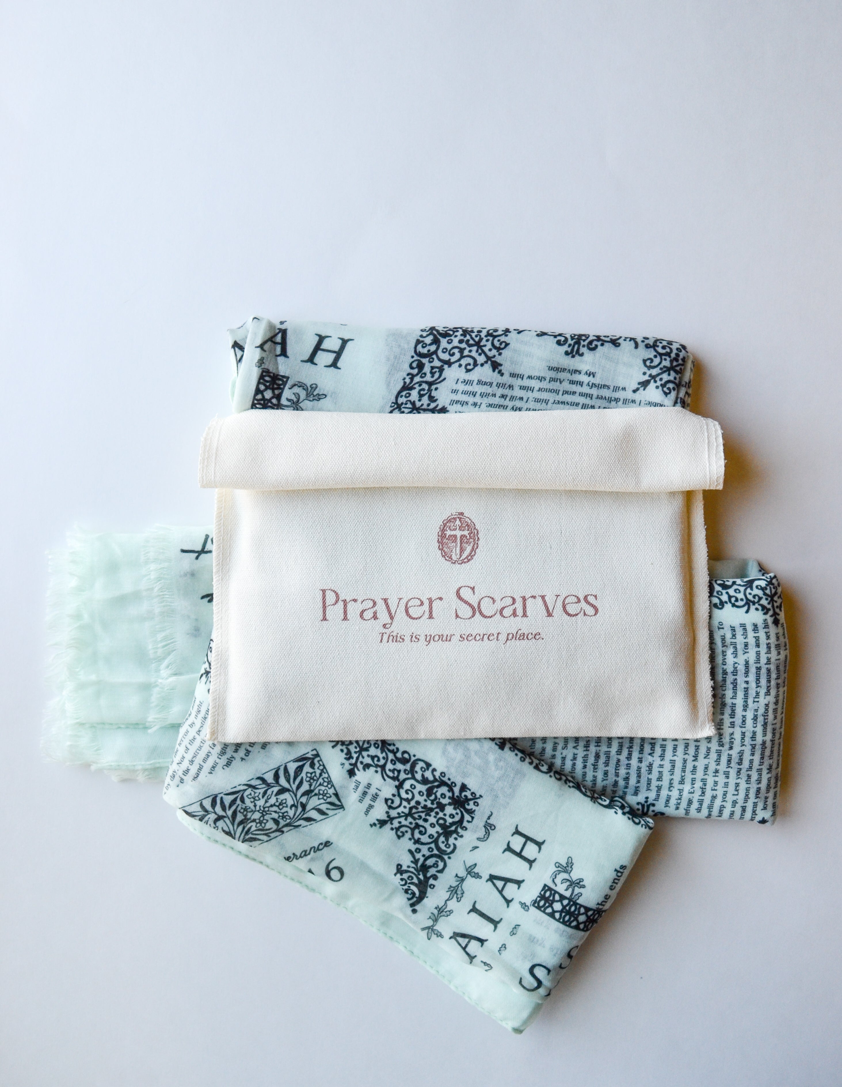 Protection prayer scarf by Prayer Scarves® in honeydew green, shown folded with branded fabric pouch, laid flat to display Scripture-printed design featuring passages about God’s protection
